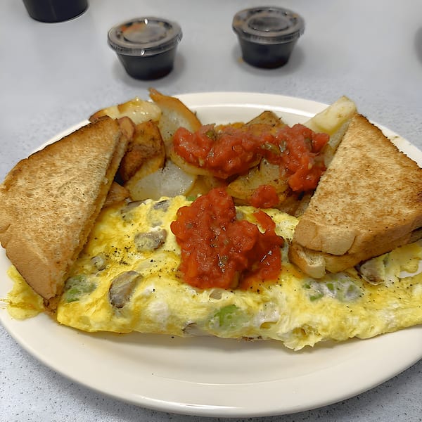A diner breakfast with an omelet topped with salsa, home fries, and toast on a white plate.